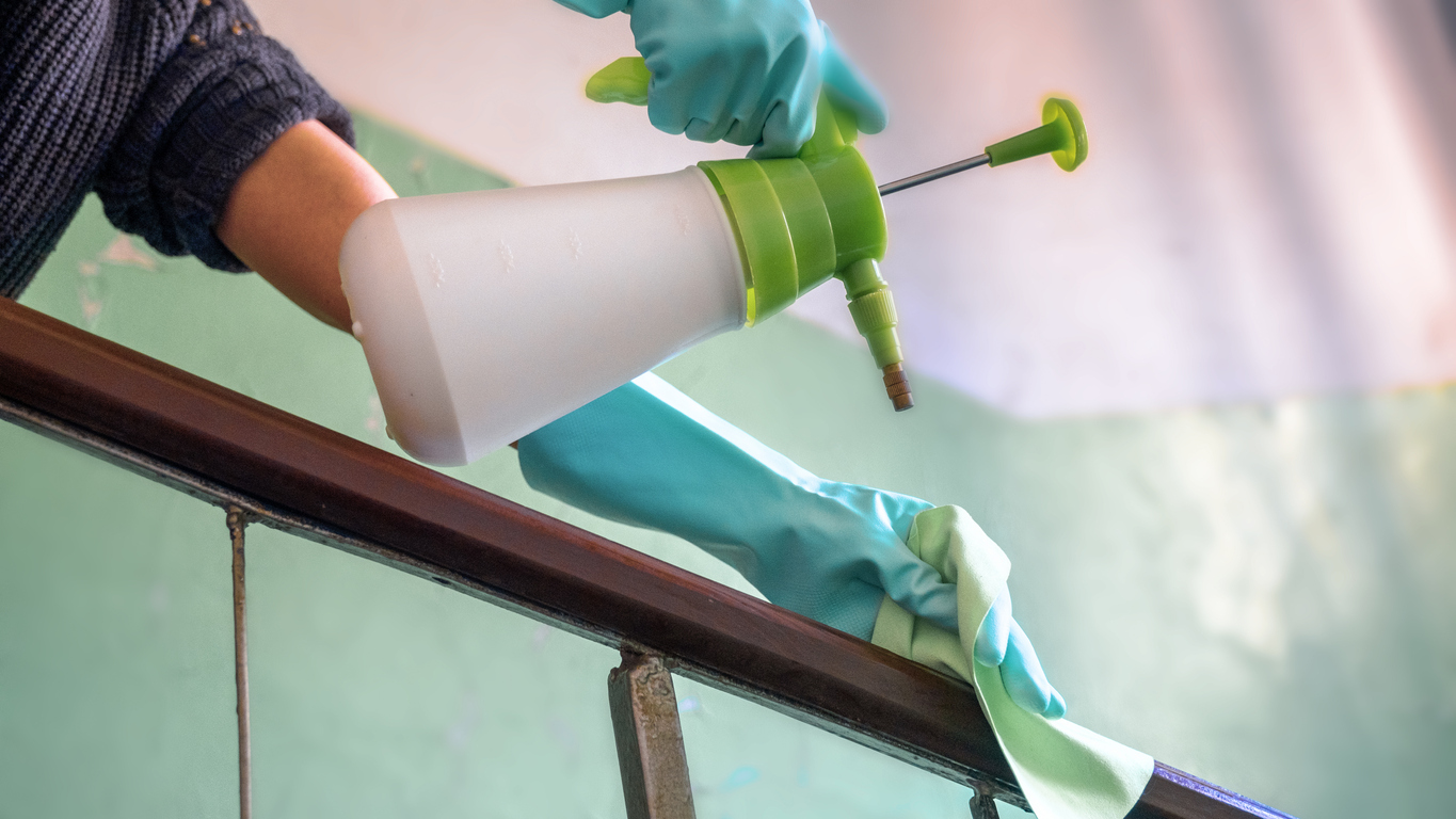 Woman wearing gloves while spraying cleaning chemicals for a home deep cleaning
